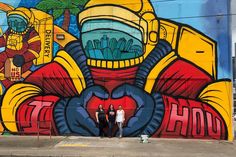 two people standing in front of a large mural