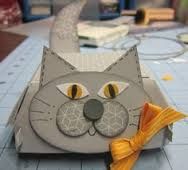 an origami cat with yellow eyes and a bow on it's head