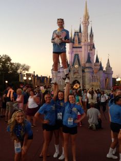 some people are standing in front of a castle and posing for the camera with their hands up