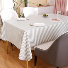 a dining room table with white chairs and a striped table cloth on top of it