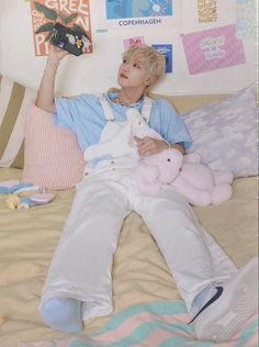 a man laying on top of a bed holding a stuffed animal next to his hand