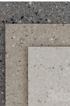 two white square tiles sitting next to each other on top of a cement floor covered in small pebbles