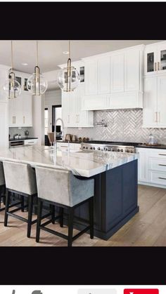 a large kitchen with white cabinets and marble counter tops, along with bar stools