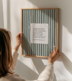 a woman holding up a framed piece of paper with a poem written on it in front of her