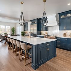 a large kitchen with blue cabinets and white counter tops, wooden flooring and pendant lights hanging from the ceiling