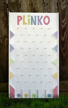 a sign that says plinko on it in front of a wooden fence with grass