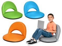 a young boy sitting on a chair with four different colored seats around him and using a laptop