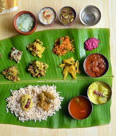 a large banana leaf with different types of food on it and sauces in bowls