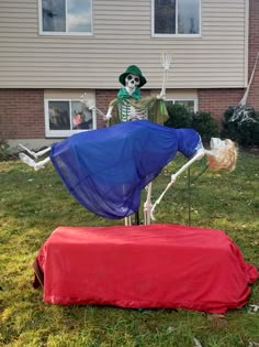 two skeleton statues in front of a house, one with a blue dress and the other red