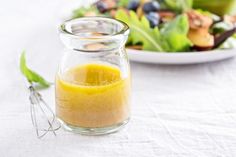 a glass jar filled with liquid next to a salad