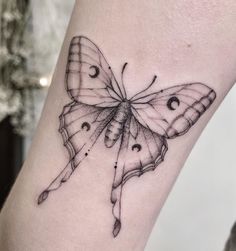 a small butterfly tattoo on the arm with eyes and nose drawn onto it's wings