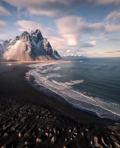 an aerial view of the beach and mountains in iceland, with waves crashing on it