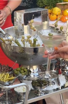 people are serving olives and other food on a silver platter at an outdoor event