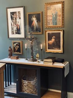 a table with pictures and candles on it in front of a wall filled with paintings