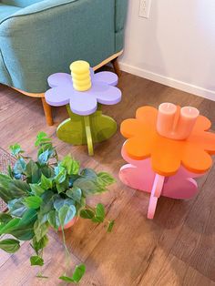 three flower shaped tables sitting on top of a wooden floor next to a green chair