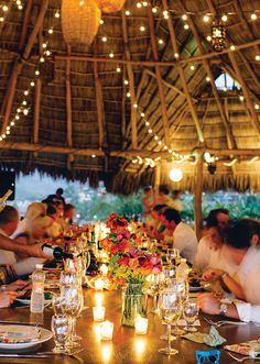 a group of people sitting around a table with wine glasses and candles on top of it