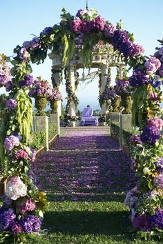 the wedding arch is decorated with purple flowers