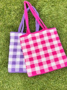 two crocheted bags sitting on top of green grass