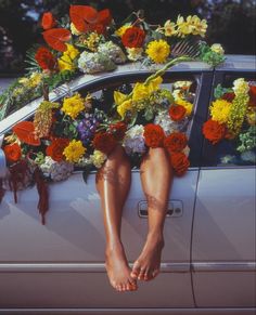 a woman's legs are propped up on the hood of a car decorated with flowers