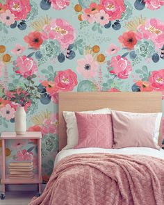 a bed with pink and blue floral wallpaper next to a wooden headboard in a bedroom