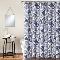 a blue and white shower curtain in a bathroom with a mirror on the wall above it