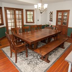 a large wooden table sitting in the middle of a living room next to two windows