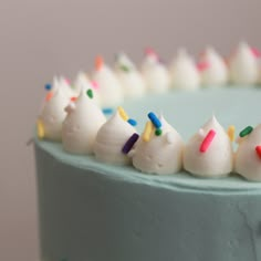 a blue cake with white frosting and colorful sprinkles on the top