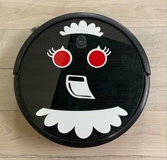 a black and white face with red eyes on a wooden floor next to a wall