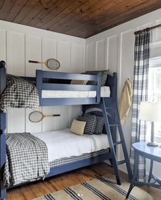 two bunk beds in a room with wood floors and white paneling on the walls