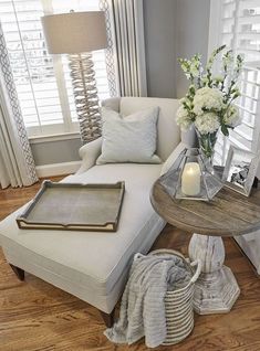 a living room filled with furniture and flowers on top of a wooden table next to a window