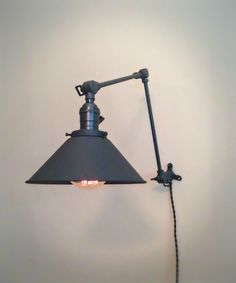 an old fashioned wall lamp with a light bulb on it's side and a cord attached to the arm