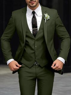 a man in a green suit and tie with his hands on his hips looking at the camera