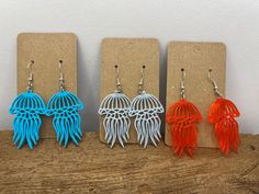 three pairs of earrings with orange, blue and white jellyfish in the shape of cages