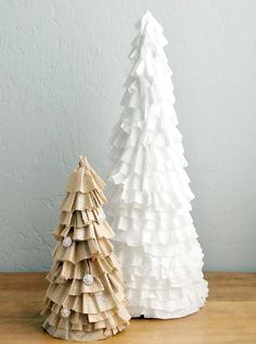 two paper christmas trees sitting on top of a wooden table