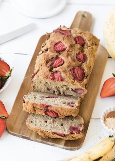 sliced loaf of strawberry bread sitting on top of a cutting board next to strawberries