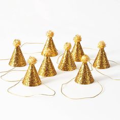 gold party hats with pom poms on top are lined up against a white background