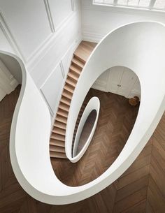 an aerial view of a spiral staircase in a house with wood floors and white walls