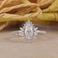 an oval cut diamond engagement ring with side stones on the band, set in 18k white gold