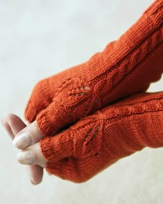 a woman's hand wearing an orange knitted glove