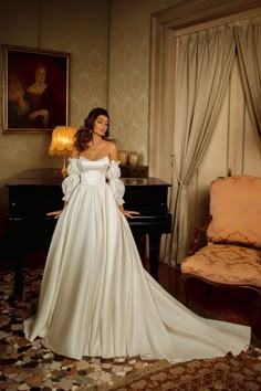 a woman in a white dress standing next to a piano