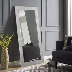 a large mirror sitting on top of a wooden floor next to a vase filled with flowers