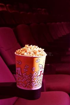 a cup filled with popcorn sitting on top of a red chair