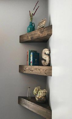 three wooden shelves with books and vases on them in the corner of a room