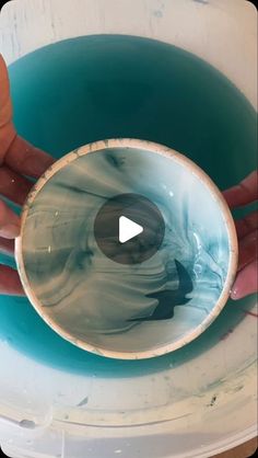 a person holding a bowl in their hand with water inside it and the bottom part of the bowl being filled with liquid