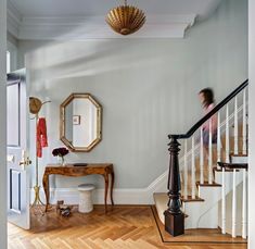 a woman is walking down the stairs in a house with white walls and wood floors