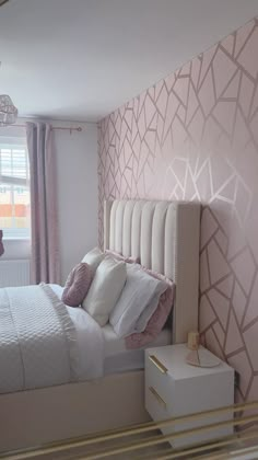 a white bed sitting next to a window in a room with pink and gold walls