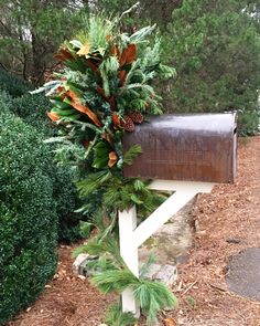 a mailbox is decorated with evergreens and pine cones