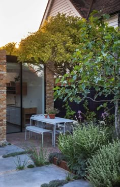 an outdoor dining area with table and chairs next to the house's brick wall