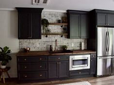 a kitchen with black cabinets and silver appliances