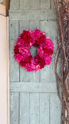 a wreath with pink flowers hanging on the side of a door